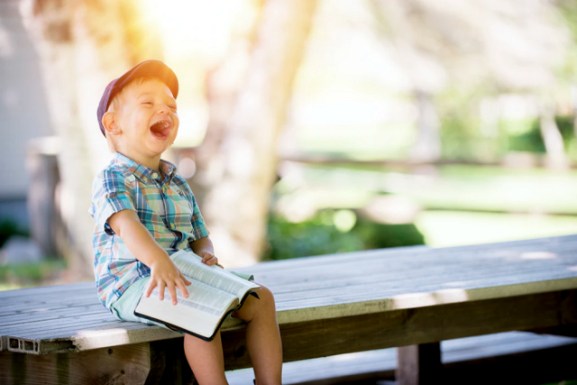 toddler-reading-book-on-bench